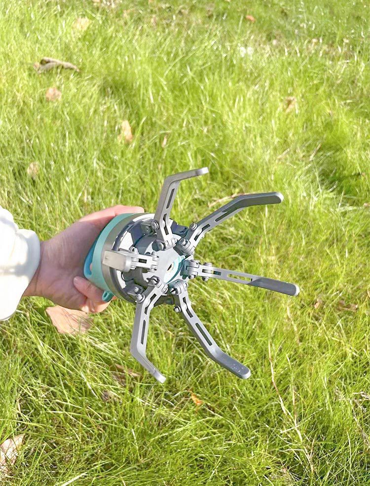 Person holding a metal tool against a grassy background